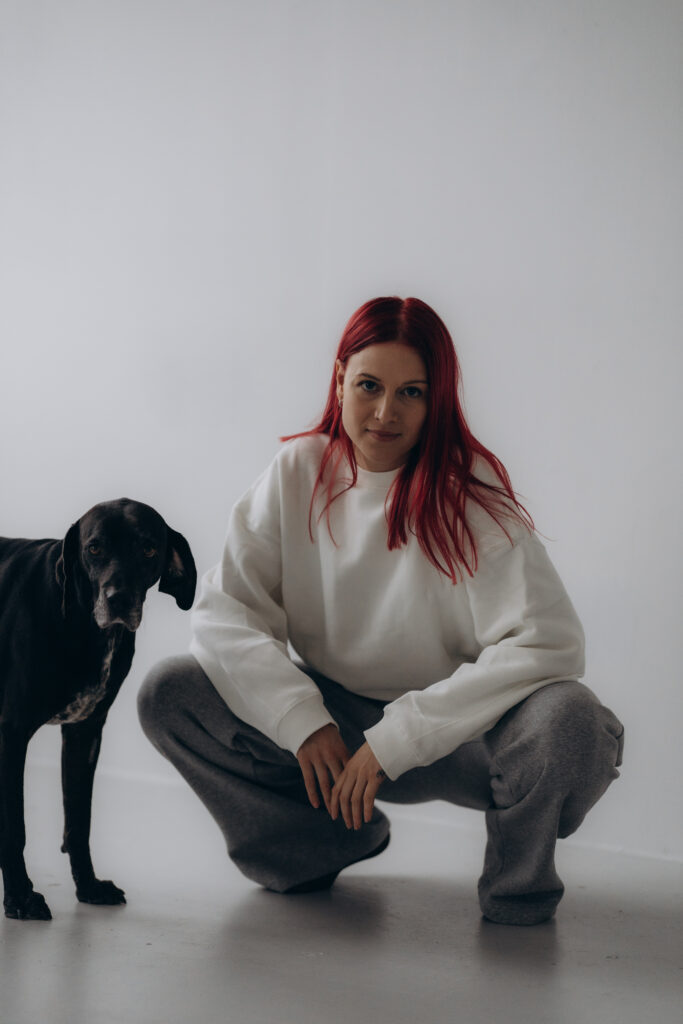 Gina crouching next to a black dog